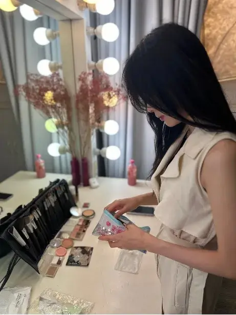 化妝師在附燈泡的化妝鏡前挑選化妝品